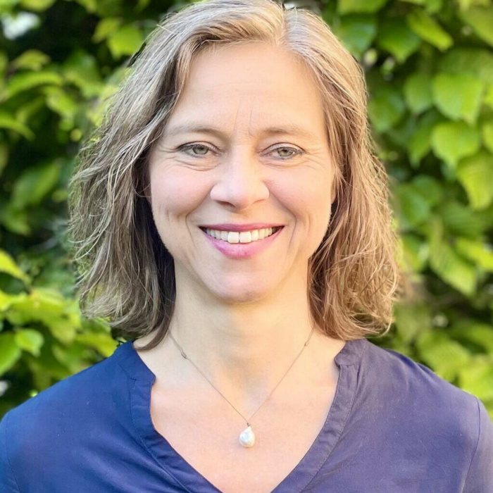 Christiane lächelt vor einem grünen Hintergrund.